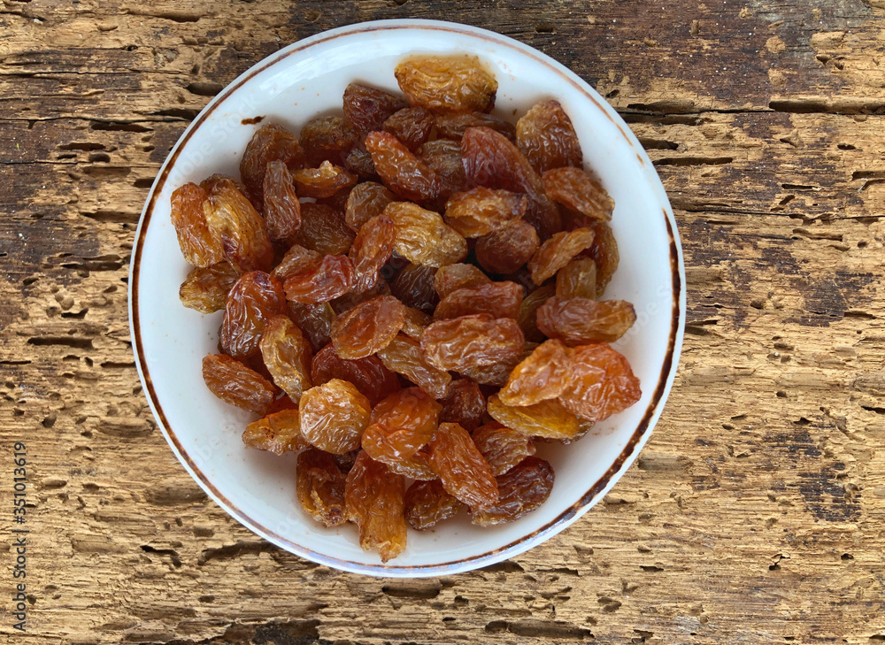 dried grapes in a bowl on a wooden table dried grapes in a bowl on a wooden table