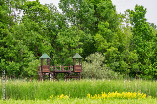 Wooden house in nature for hunters and bird photographers. Hunting watchtower. Wooden lookout tower for birdwatchin photo