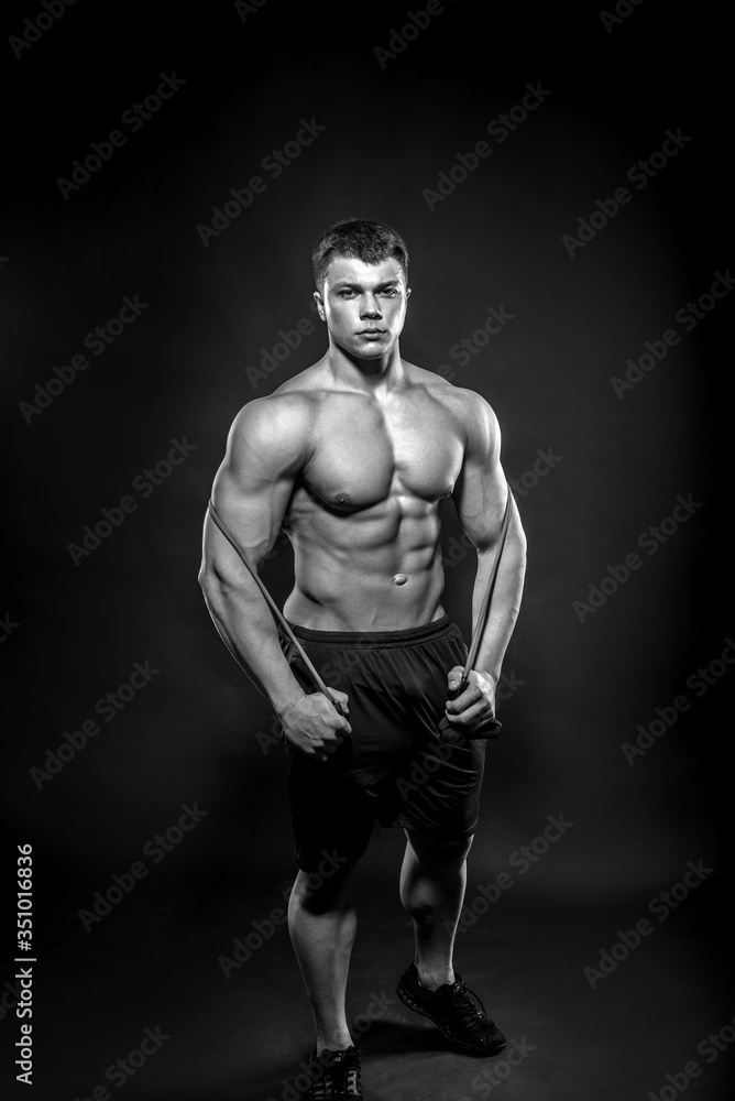 Sexy young athlete posing on a black background in the Studio. Fitness, bodybuilding, black and white Sexy young athlete posing on a black background in the Studio. Fitness, bodybuilding, black and white