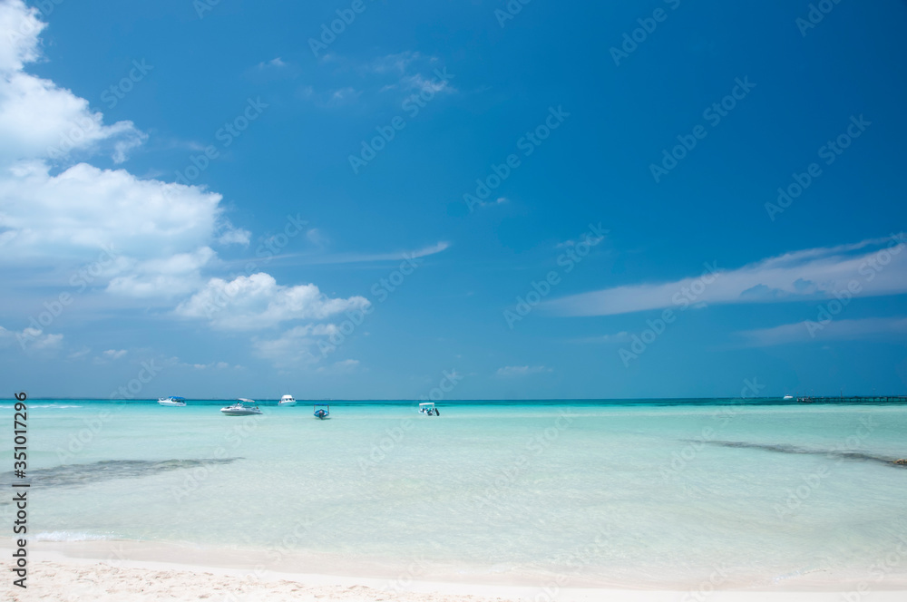 Empty beach, small boats in the sea. Idyllic tropical beach in the Caribbean sea of Isla Mujeres, Mexico