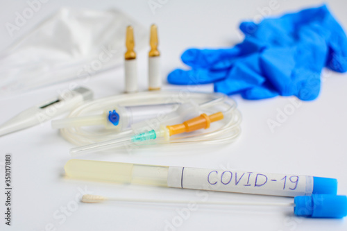 Coronavirus 2019. Laboratory tube with a sample, gloves, mask, thermometer, dropper, medicine on a white background. Diagnosis and treatment of Covid-19.