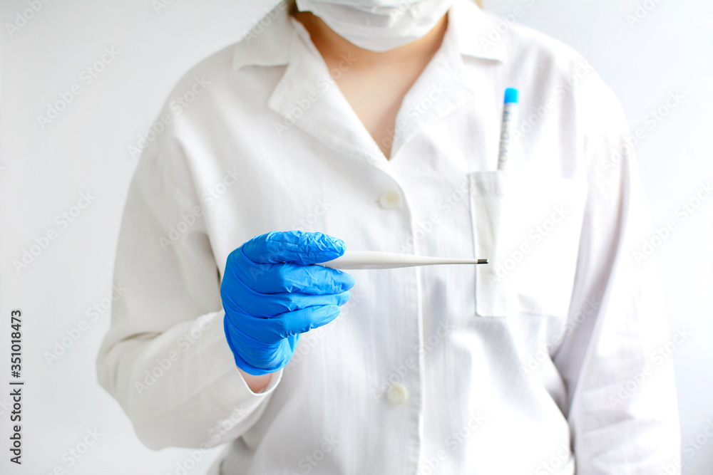 A doctor in a white coat and blue gloves holds a thermometer in his hands. A doctor in a white coat and blue gloves holds a thermometer in his hands.