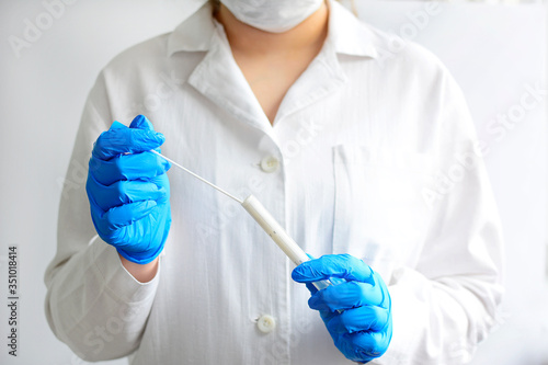 A blue-gloved technician takes a mucus sample for laboratory diagnosis of viral diseases. The concept of diagnosis of viral and bacterial diseases