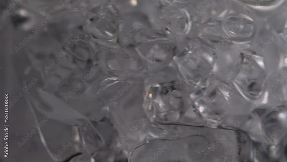 Throws ice cubes in a glass cup. Cold whiskey. Slow motion. Throws ice cubes in a glass cup. Cold whiskey. Slow motion.