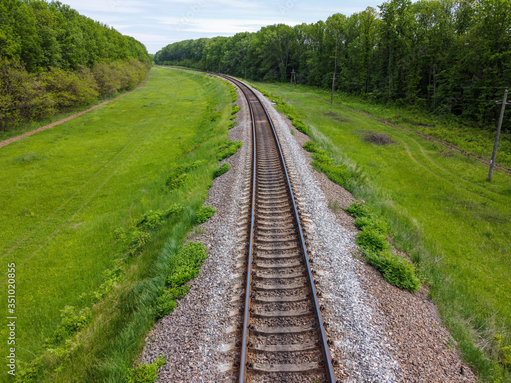 Railway tracks, a road for food that passes through beautiful nature, green grass, trees and spring weather. Railway tracks, a road for food that passes through beautiful nature, green grass, trees and spring weather.
