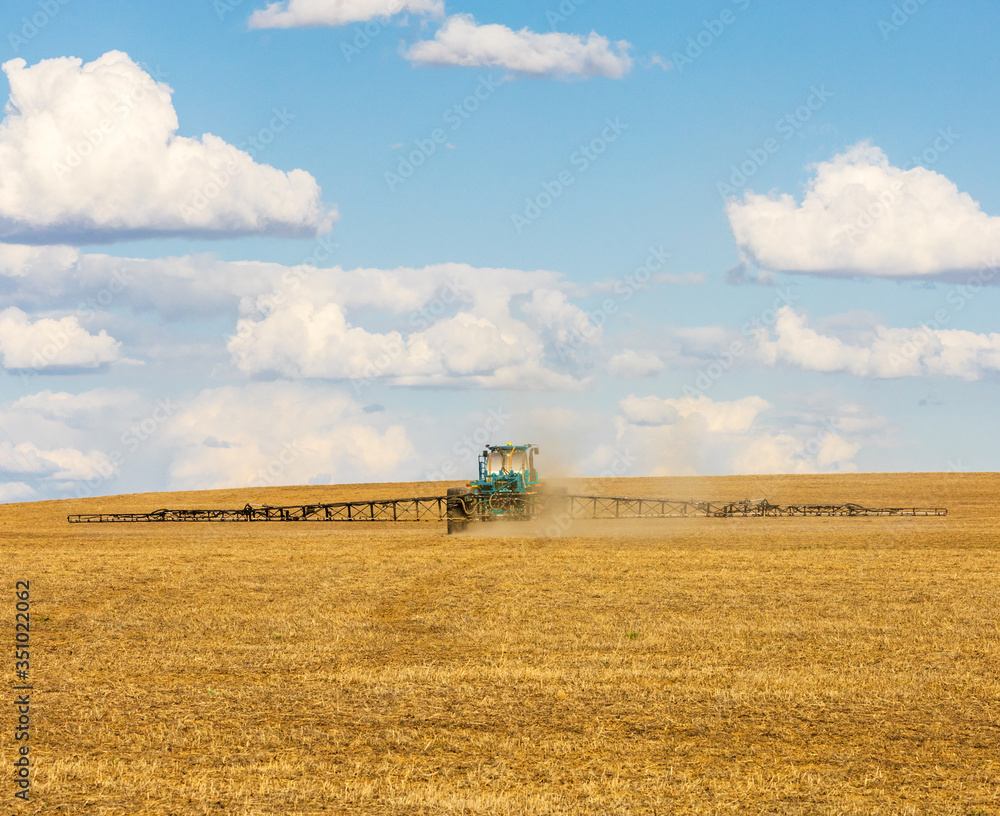 Fototapeta premium Tractor spraying crops on the prairies