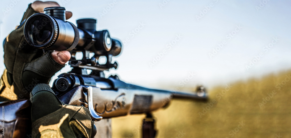 Hunt hunting rifle. Hunter man. Hunting period. Male with a gun. Close up. Hunter with hunting gun and hunting form to hunt. Hunter is aiming. Shooter sighting in the target