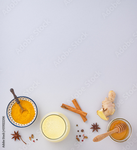 a glass of Golden milk with turmeric, spices and honey on gray background. strengthens the immune system drink