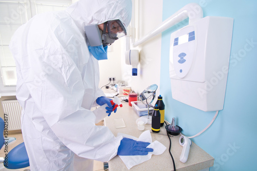 Doctor in protective suit uniform and mask cleans the laboratory.