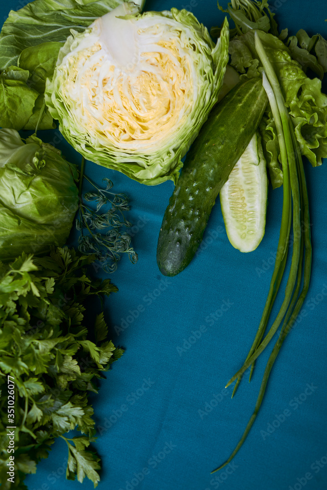 Obraz premium Close-up of fresh green vegetables on green tablecloth, selective focus
