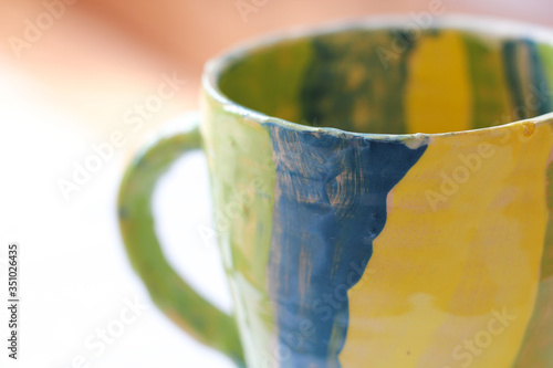 Ceramic handmade cup in yellow green and blue color
