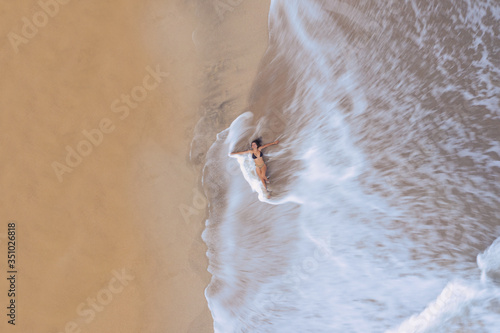 woman laying down at the beach, surrounded by waves