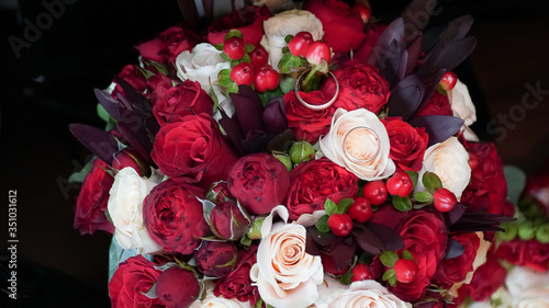 Bouquet of red roses and rings on flowers.