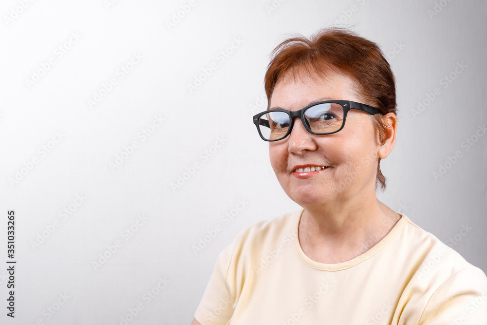 senior woman looks away with glasses on a white background in a light T-shirt. place for text, isolated senior woman looks away with glasses on a white background in a light T-shirt. place for text, isolated