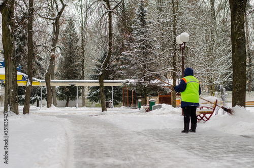 snow storm in the city. Roads and sidewalks covered with snow. Worker shovel clears snow. Bad winter weather. Street cleaning after snowstorm.