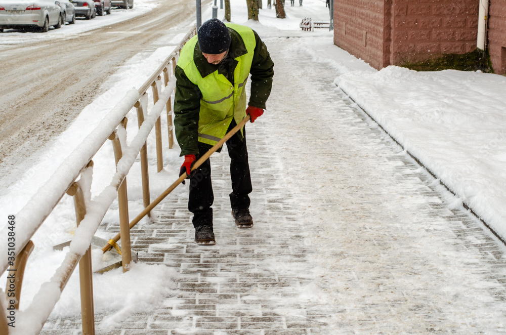 snow storm in the city. Roads and sidewalks covered with snow. Worker shovel clears snow. Bad winter weather. Street cleaning after snowstorm. snow storm in the city. Roads and sidewalks covered with snow. Worker shovel clears snow. Bad winter weather. Street cleaning after snowstorm.