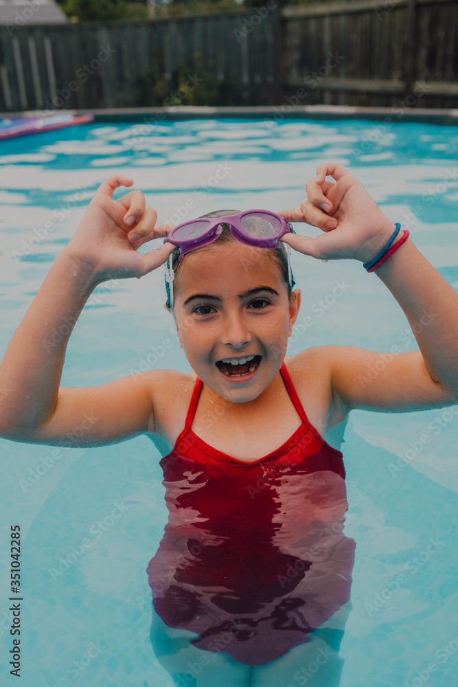 chica joven divirtiéndose en la piscina en un día caluroso de verano con gafas acuáticas en