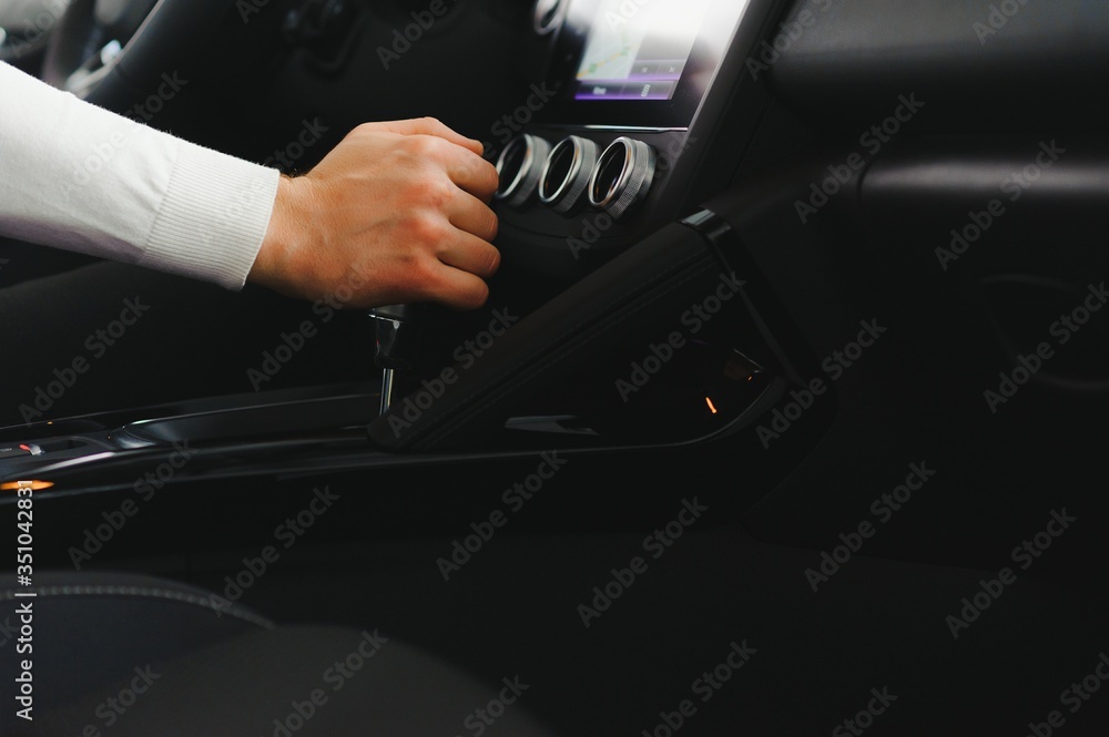 Male hand on the shift lever of the transmission in the car