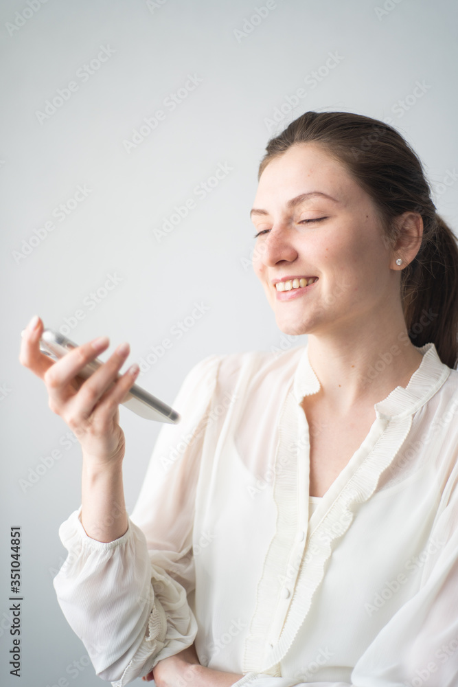 A happy woman communicates with a voice assistant on her phone. Reaction to a personal assistant's response A happy woman communicates with a voice assistant on her phone. Reaction to a personal assistant's response