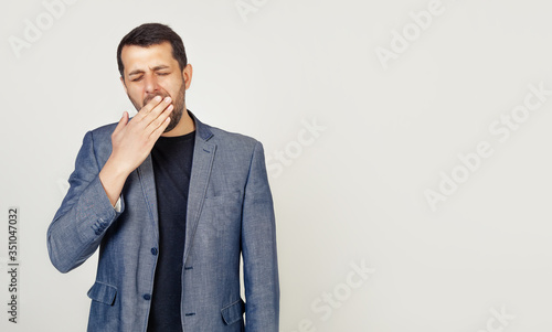 Business man on an isolated background bored yawns tired hand covering his mouth