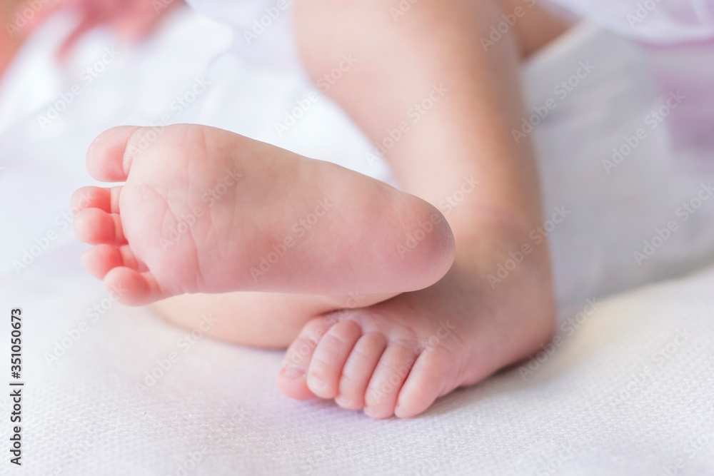 Baby feet on white coverlet. Toes. Horizontal photo. Macro. Close-up. Little feet, focus on one leg, the second leg on the background. Baby feet on white coverlet. Toes. Horizontal photo. Macro. Close-up. Little feet, focus on one leg, the second leg on the background.
