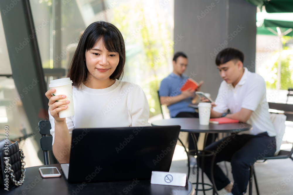 Asian young man and woman sitting one person per one table for distance of 6 feet distance protect from COVID-19 viruses for social distancing for infection risk at coffee cafe.. Asian young man and woman sitting one person per one table for distance of 6 feet distance protect from COVID-19 viruses for social distancing for infection risk at coffee cafe..