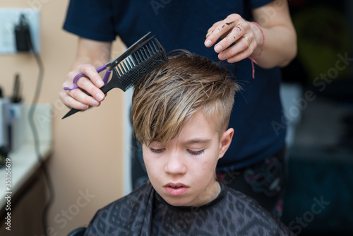 Mom cuts the hair of her son at home during quarantine amid COVID-19 
coronavirus pandemic