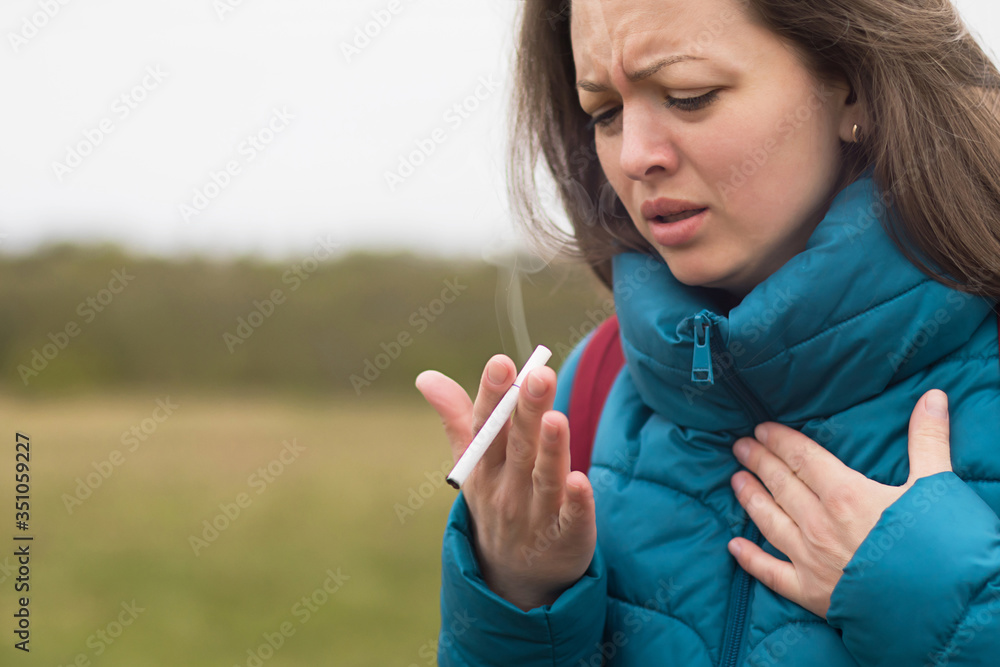 Young woman, girl smoking a cigarette and coughing, problem with lungs. Cigarette addiction