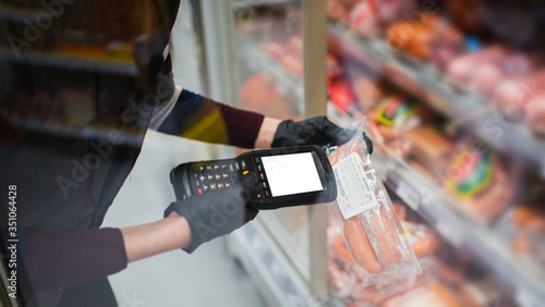 barcode scanner in hand in rubber gloves checks the price of products in the supermarket. close-up view photo