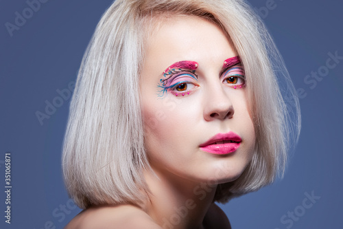 Beauty and Fashion Concepts. Closeup Beauty Portrait of Young and Fresh Caucasian Girl with Vivid Artistic Makeup. Against Gray.