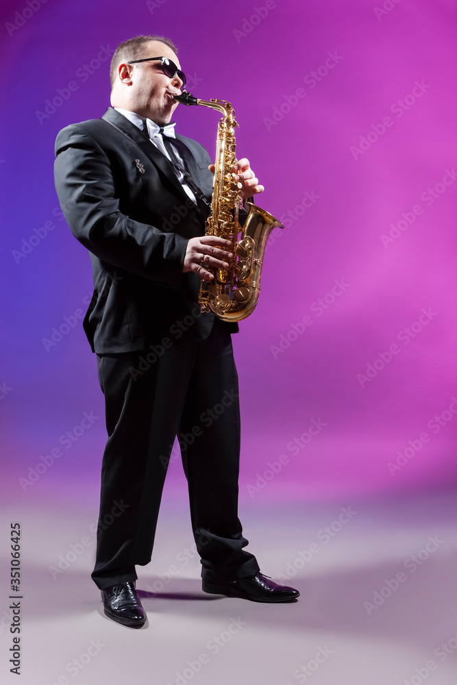 Fototapeta premium Music and Musicians Concepts. Full length Portrait of Mature Expressive Caucasian Saxophonist Against Colorful Background.