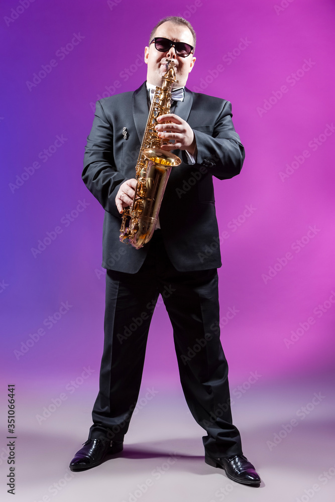 Naklejka premium Musicians Concepts. Full Length Portrait of Mature Expressive Caucasian Saxophonist Against Colorful Background.