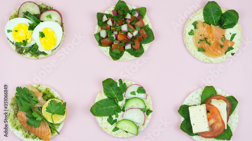 Beautiful six rice cakes sandwiches with different healthcare ingredients on pink background.Tasty rice cakes with tomatoes, salmon, mint and others fit vegetables. Healthcare food concept