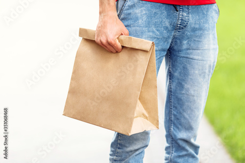 courier holds an empty paper bag of food. Delivery of goods from a store or restaurant home.