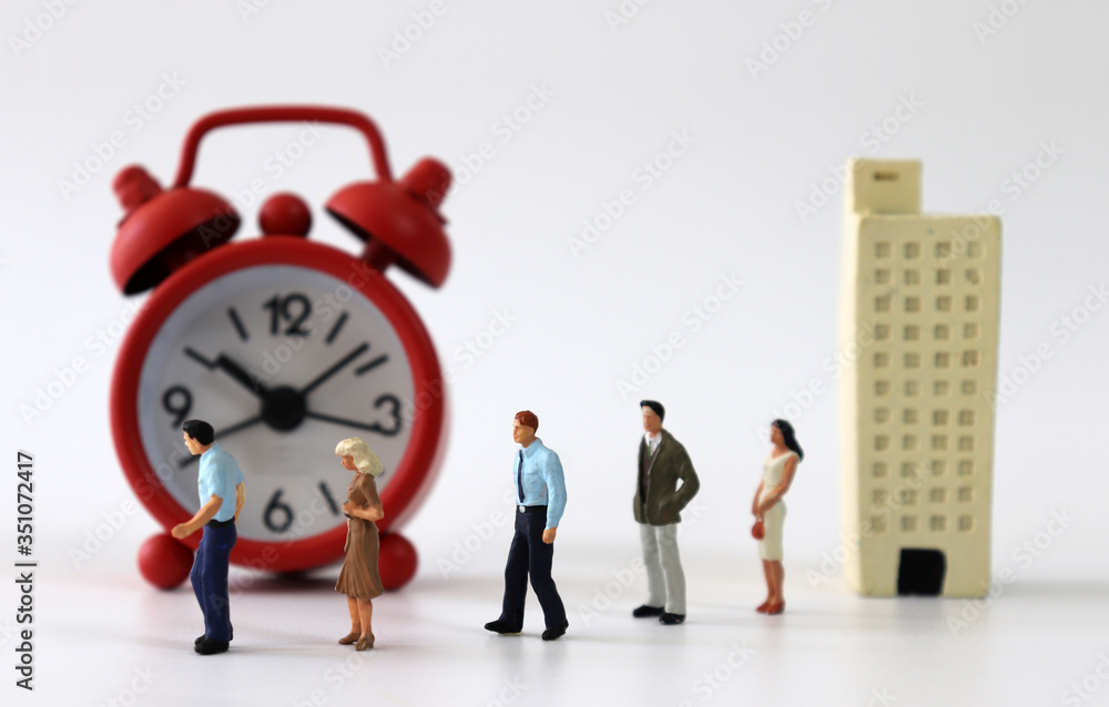Miniature people walking toward the alarm clock from the miniature building.
Miniature people walking toward the alarm clock from the miniature building.
