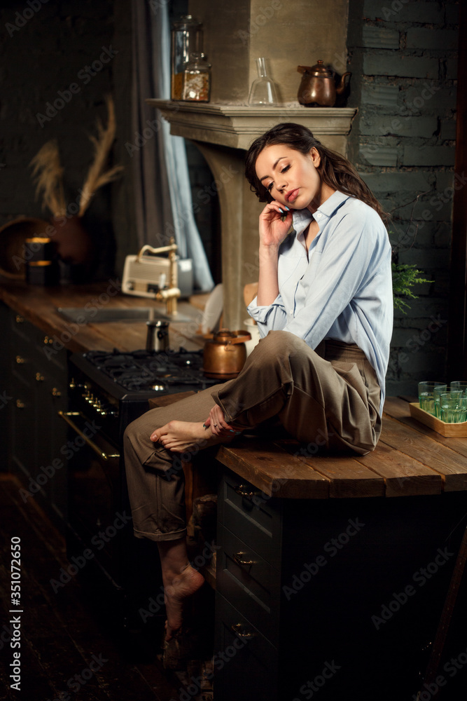 Girl alone in the kitchen. A woman in the dark kitchen at night. Girl alone in the kitchen. A woman in the dark kitchen at night.