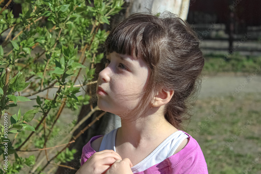 A cute little girl near the trees looks up. A cute little girl near the trees looks up.