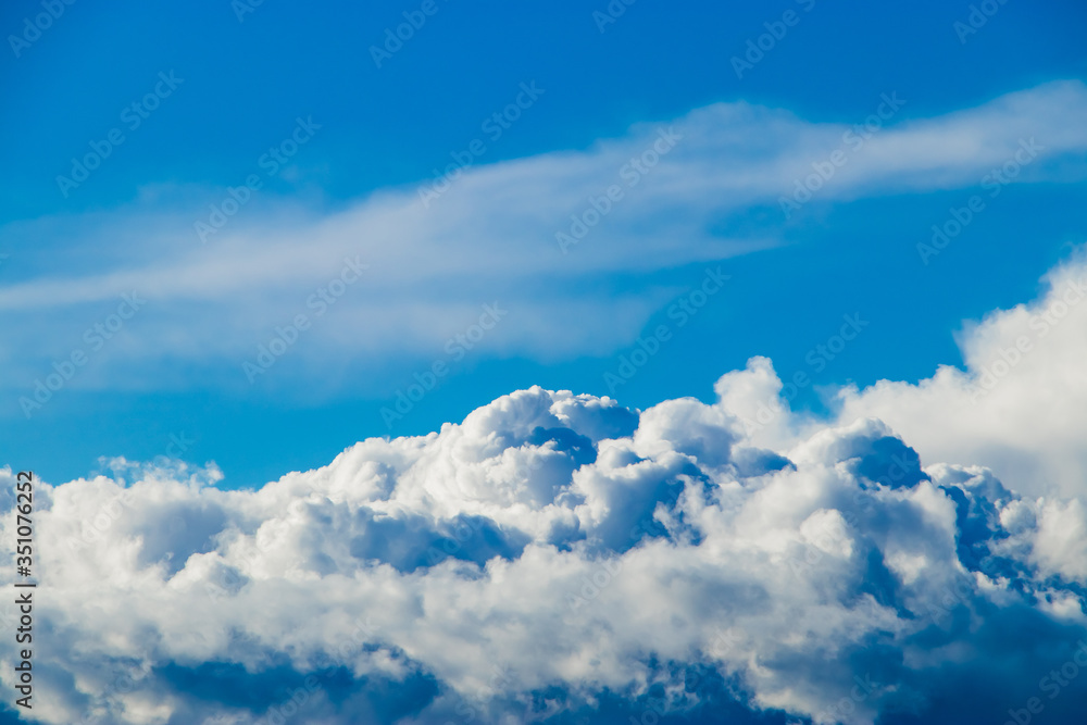 White fluffy cumulus clouds against a blue sky. A symbol of dreams and freedom. Background for design. White fluffy cumulus clouds against a blue sky. A symbol of dreams and freedom. Background for design.