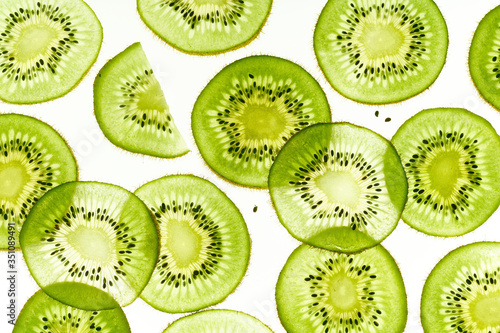 Backlit kiwi fruit slices on white background. Top view layout