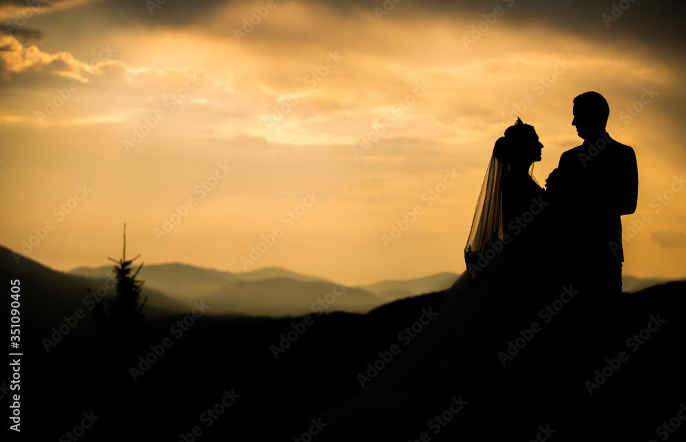 At sunset in the mountains with sunshine promises, a girl looks at a guy. Wedding Day