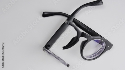 Rotating broken black glasses with diopters on a white background.Close-up.
