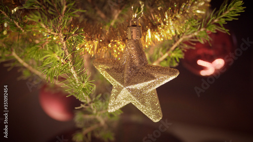 Defocused Glittering Golden Star. Christmas Decorations Hanging on Christmas Tree.