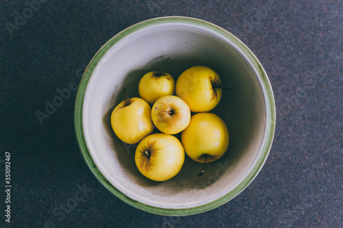 plant-based ingredients, group of golden delicious apples in bowl on kitchen countertop