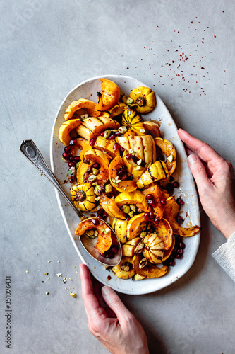 Hands holding a plate of roasted delicata squash with brown butter.