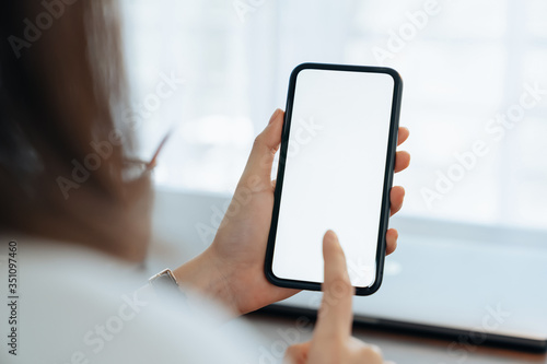 Closeup of young woman hand holding smartphone on the table and the screen is blank, social network concept.