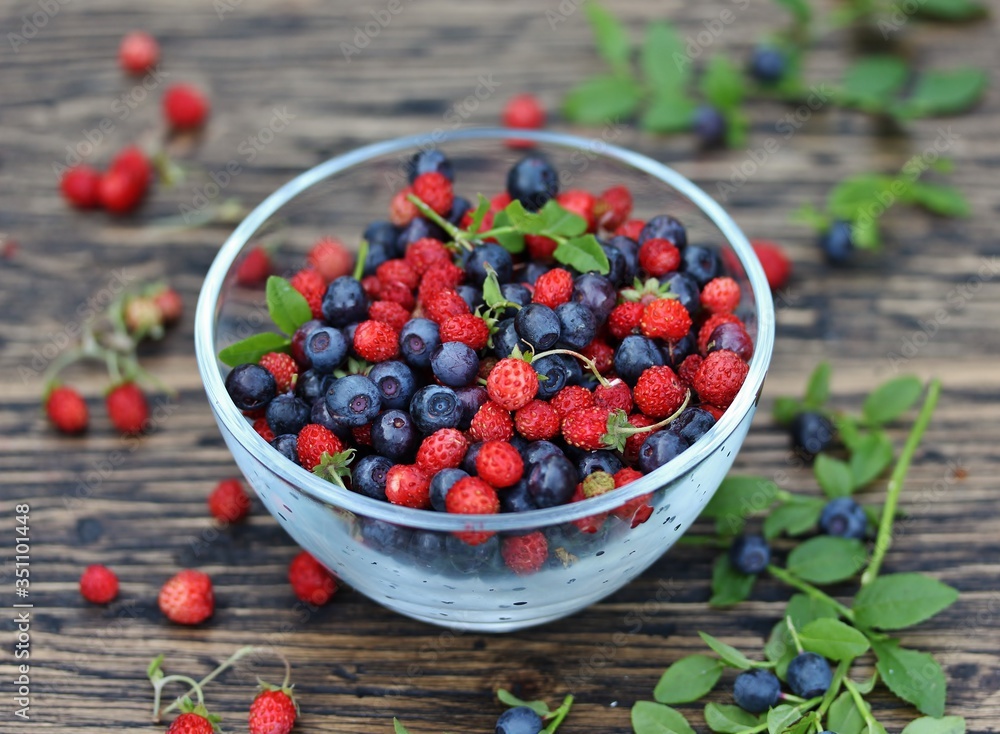 berries of wild strawberries and forest blueberries on a background of nature on an old rustic board. Country style. Soft focus. Space for text berries of wild strawberries and forest blueberries on a background of nature on an old rustic board. Country style. Soft focus. Space for text