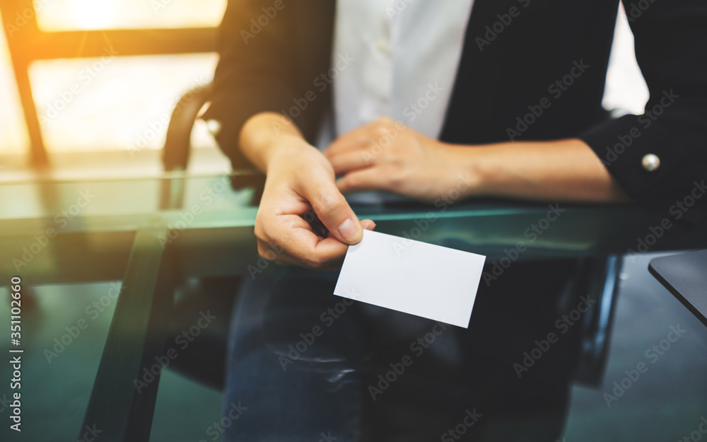Businesswoman holding and giving a blank business card to someone Businesswoman holding and giving a blank business card to someone