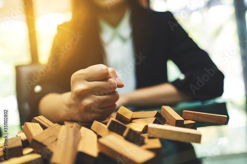 Businesswoman get angry and smashed down wooden blocks of Tumble tower game on table