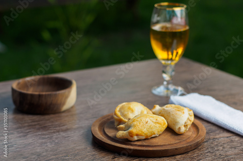 Argentine empanadas on a wood plate and beer outside