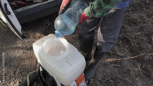 Man is filling up his backpack sprayer with water. Close up shot. one person.